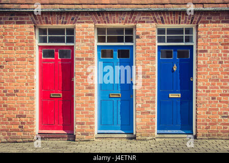 Three differently coloured front doors at the entrance of old English terraced houses. Canterbury, England. Stock Photo