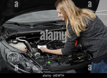 Woman checking the oil level of car engine Stock Photo