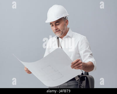 Professional architect checking a house blueprint, he is wearing a safety helmet Stock Photo