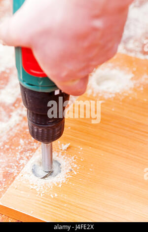 Man drilling holes for concealed hinges process closeup Stock Photo
