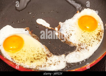 Two fried eggs on frying pan with black pepper Stock Photo