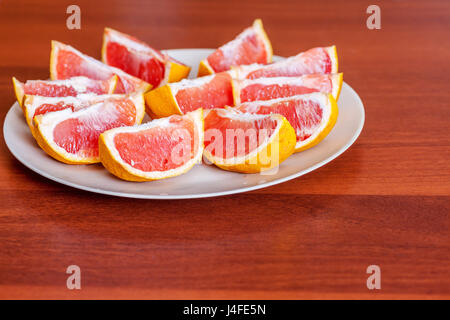 Two grapefruits sliced on lobes on plate Stock Photo
