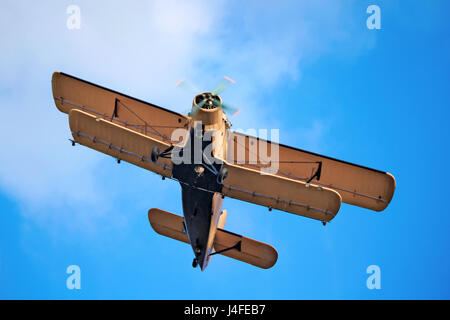 A yellow Antonov AN-2 airplane in front of blue sky, shot from below. This is an agricultural version of the An-2, used mainly for crop-spraying. Stock Photo