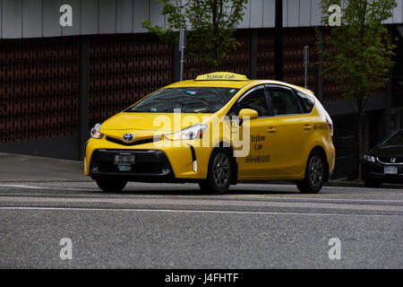 A yellow taxi in Vancouver, Canada. The building stands in the downtown district of the city. Stock Photo