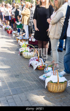 Families with their cane baskets covered with embroidered napkins with Easter offerings of eggs and cakes to celebrate the Russian Orthodox Easter. Stock Photo