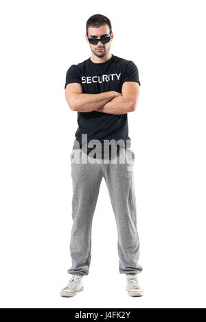 Tough serious bouncer or bodyguard with crossed arms staring at camera. Full body length portrait isolated on white studio background. Stock Photo