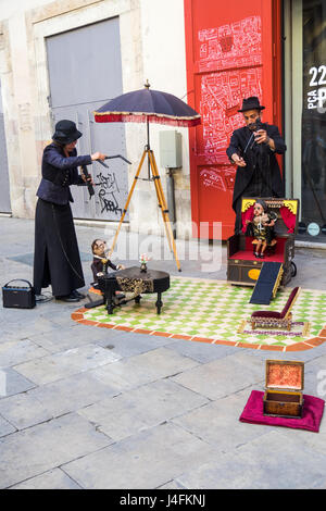 A male and female puppeteer and their marionettes performing a street theatre in the Gothic Quarter of Barcelona, Spain. Stock Photo