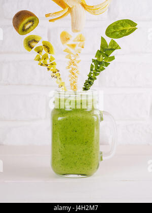 Smoothie ingredients. Kiwi, banana and spinach and green smoothie in mason jar. Superfoods and healthy lifestyle or detox diet food concept. Flying or Stock Photo