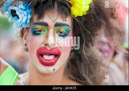 RIO DE JANEIRO - FEBRUARY 25, 2017: A Brazilian man celebrates carnival with brightly colored makeup and a disheveled wig at a street party in Ipanema Stock Photo