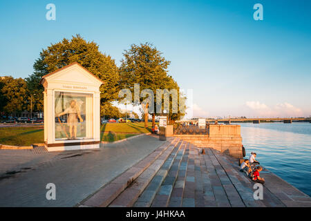Riga, Latvia - July 1, 2016: People resting on staircase near St Christopher, Or Big Kristaps Statue Sculpture At City Promenade Embankment Near Dauga Stock Photo