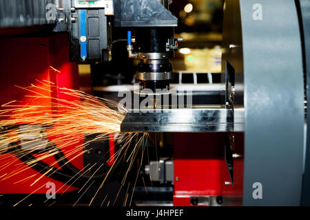 CNC laser cutting metal pipe with bright sparkle in factory. Industry machine. Stock Photo
