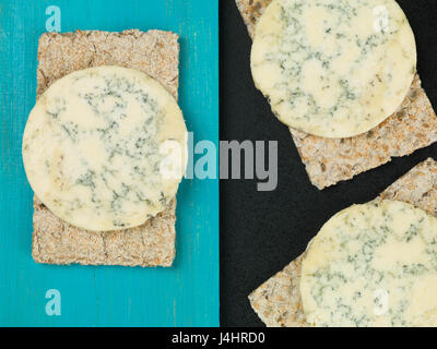 Blue Stilton Cheese on Thin Crisp Wholewheat Crackers Against a Blue and Black Background Stock Photo
