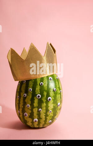 Freak watermelon wearing a crown on a pink background Stock Photo