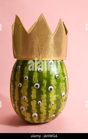 Freak watermelon wearing a crown on a pink background Stock Photo