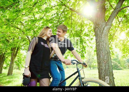 A loving couple on bicycle is smiling in the park Stock Photo