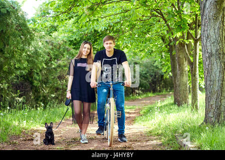 Portrait of a loving couple on bicycle with  dog in the park Stock Photo