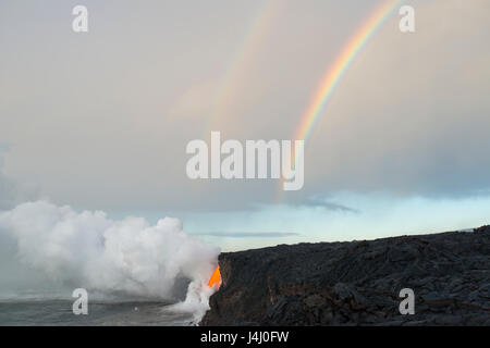 a double rainbow touches down where hot lava from Kilauea Volcano enters the ocean from the open end of a lava tube at Kamokuna, Hawaii Island, USA Stock Photo