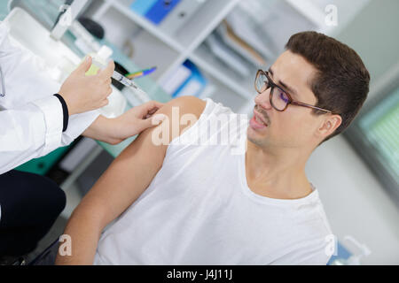 Nervous man having injection in arm Stock Photo