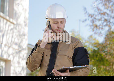 construction engineer talking on phone and holding clipboard Stock Photo