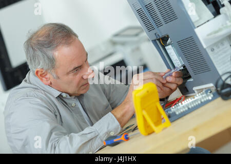 Senior technician using screwdriver Stock Photo