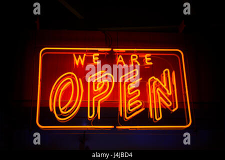 Open neon sign against dark background showing open for business Stock Photo