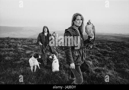 Falconers Steve and Emma Ford posing with their falcons and hunting dogs on the moors in Gleneagles, Scotland. Derek Hudson / Alamy Stock Photo Stock Photo