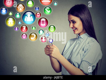 Mobile communication technology concept. Happy young woman using texting on smartphone with application symbols icons flying out of screen Stock Photo