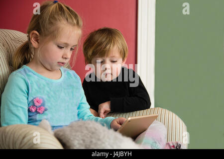 brother and sister playing on electronic tablet together Stock Photo