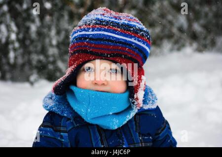 adorable toddler boy playing outside in cold snow Stock Photo