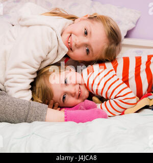adorable brother and sister siblings hugging on bed together Stock Photo