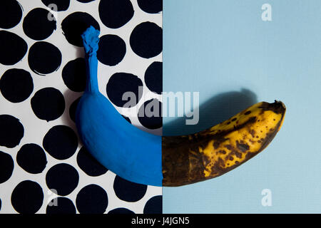 A half-painted banana blue Each half opposing the plain background and dots Stock Photo