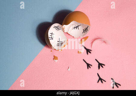 The counting of the days on a broken egg with footprint on a pink and blue background Stock Photo