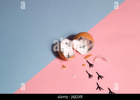 The counting of the days on a broken egg with footprint on a pink and blue background Stock Photo