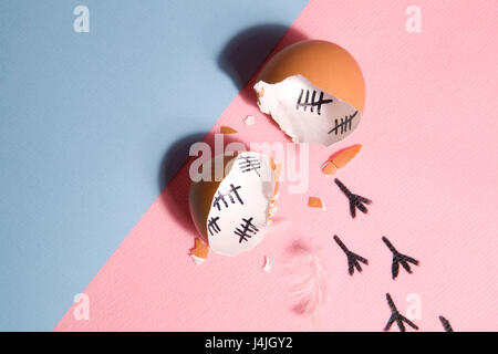 The counting of the days on a broken egg with footprint on a pink and blue background Stock Photo