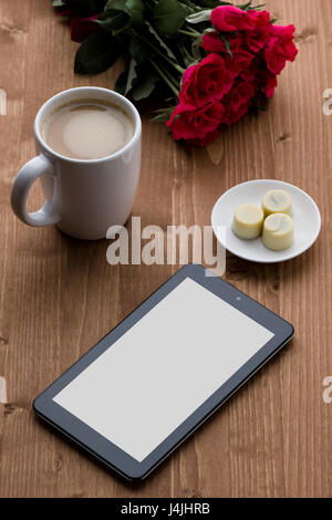 black tablet on table with coffe, chocolate and roses Stock Photo