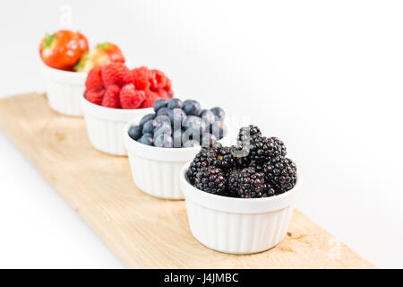 Blackberries, blueberries, raspberries and strawberries on wooden cutting board with shallow depth of field Stock Photo