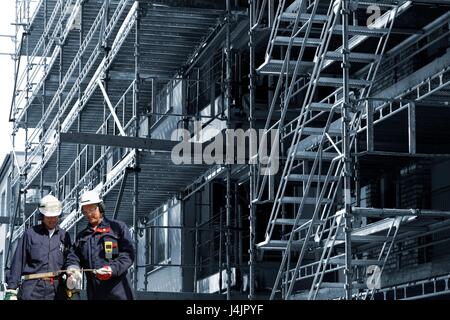 Construction workers on site with scaffolding on building. Stock Photo