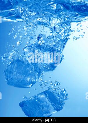 Ice cubes falling into water, studio shot. Stock Photo