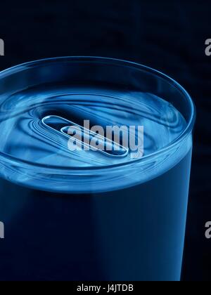 Paperclip floating on water in a glass, studio shot. Stock Photo