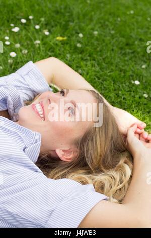 Young woman lying on grass smiling. Stock Photo