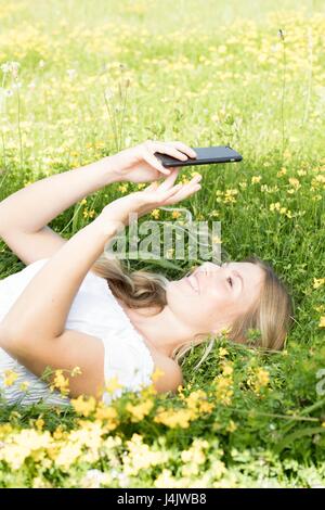 Young woman lying on grass with cell phone. Stock Photo