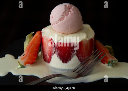 Panna cotta dessert with fresh strawberries, strawberry ice-cream and vanilla sauce. Stock Photo