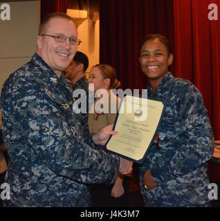 170208-N-SP496-012 SILVERDALE, Wash. (Feb. 8, 2017) – Capt. Alan Schrader, Naval Base Kitsap (NBK) commanding officer, presents Culinary Specialist Seaman Alisha Goins with the Good Conduct Medal during an all-hands call held at the NBK-Bangor Theater. More than 30 awards and decorations were bestowed to NBK personnel during the event. (U.S. Navy photo by Petty Officer 3rd Class Jane Wood/Released) Stock Photo