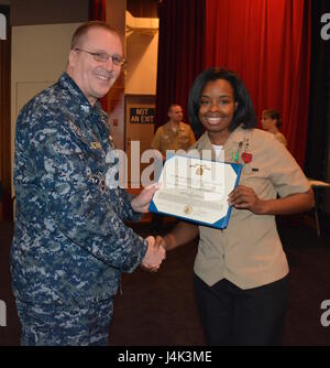 170208-N-SP496-027 SILVERDALE, Wash. (Feb. 8, 2017) – Capt. Alan Schrader, Naval Base Kitsap (NBK) commanding officer, presents Electronics Technician 2nd Class Cierra Staples with the Navy and Marine Corps Achievement Medal during an all-hands call held at the NBK-Bangor Theater. More than 30 awards and decorations were bestowed to NBK personnel during the event. (U.S. Navy photo by Petty Officer 3rd Class Jane Wood/Released) Stock Photo