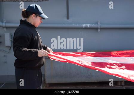 170320-N-WH681-049 ATLANTIC OCEAN (March 20, 2017) Hospitalman Tyler Radcliff folds the ensign on the fantail of the amphibious assault ship USS Kearsarge (LHD 3). Kearsarge is currently underway conducting routine shipboard certifications. (U.S. Navy photo by Mass Communication Specialist Seaman Kaitlyn E. Eads/Released) Stock Photo