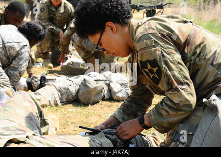 Soldiers assigned to Headquarters Support Company, 70th Brigade Support Battalion, 210th Field Artillery Brigade, 2nd Infantry Division/ROK-US Combined Division, applies a tourniquet to a simulated casualty during a field training exercise at LTA130, South Korea, May 3, 2017. The week long FTX provides Soldiers training opportunities under simulated combat conditions. (U.S. Army photo by Cpl. Michelle U. Blesam, 210th FA Bde PAO) Stock Photo