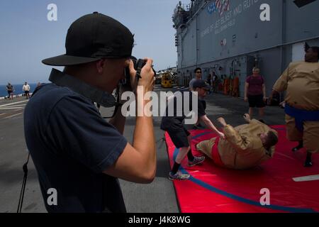 170505-N-KD168-041 U.S. 5TH FLEET AREA OF OPERATIONS (May 5, 2017) Seaman Kai Vinson takes photos of a sumo wrestling game during a steel beach picnic aboard the amphibious assault ship USS Bataan (LHD 5). The ship is currently deployed with the Bataan Amphibious Ready Group in support of maritime security operations designed to reassure allies and partners and preserve the freedom of navigation and the free flow of commerce in the region. (U.S. Navy photo by Mass Communication Specialist 2nd Class Magen F. Reed/Released) Stock Photo