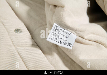 Garment, label, nursing instructions clothes, clothing, textiles, upper top, shirt, fed, beige, clothing, child clothes, child clothing, nursing label, information, tip, instructions, care, cleaning, washing, icons, laundry symbols, entries, materials, material mix, nursing icons, washing instructions, instruction, close up Stock Photo