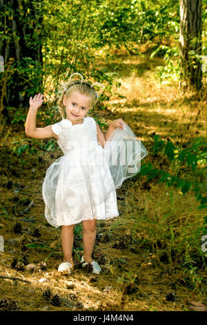 picture of little girl in a beautiful dress walks in the woods Stock Photo