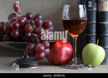 Vintage still life with fruits in bowl and wineglass near old books Stock Photo